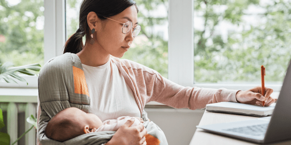 Woman holding baby while writing