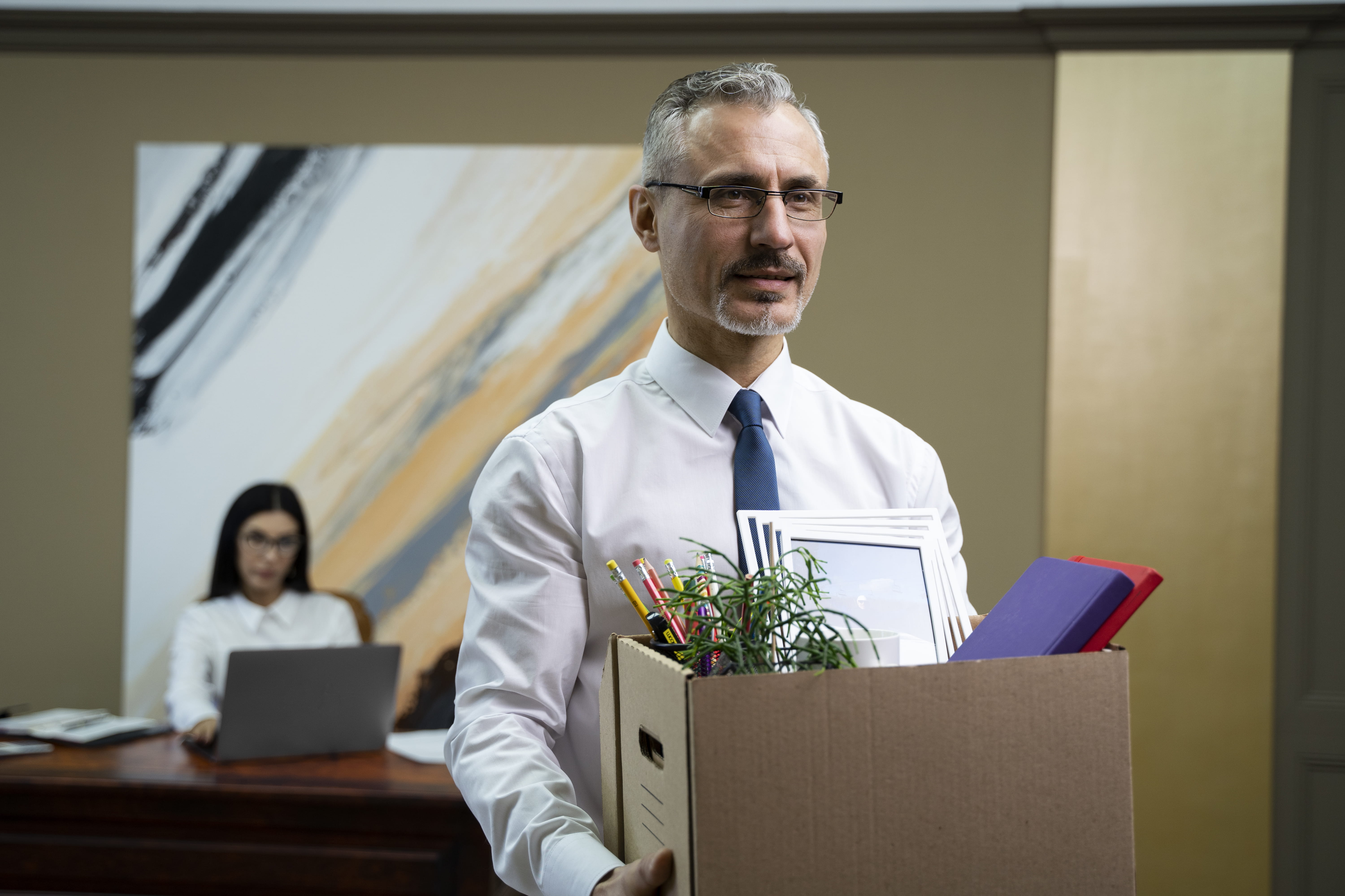 Man draagt kartonnen doos met kantoorspullen terwijl hij wegloopt van kantoor